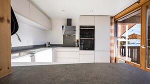 Une cuisine moderne avec des meubles blancs, un plan de travail en granit et des appareils électroménagers intégrés, notamment une cuisinière et un four.