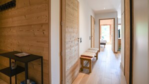 A hallway with wooden walls and doors, a bench, and a small table with a tray.