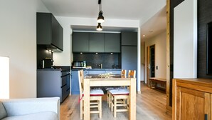 A modern kitchen with dark cabinets, a wooden dining table, and a bench.