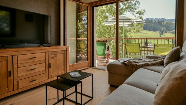 A modern living room with a television, wooden cabinet, and a sofa.