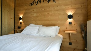 A wooden-paneled room with a bed, two wall-mounted lights, and a mountain silhouette decoration.