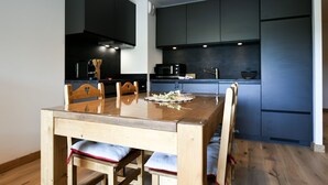A modern kitchen with dark cabinetry, a wooden dining table, and a built-in microwave.
