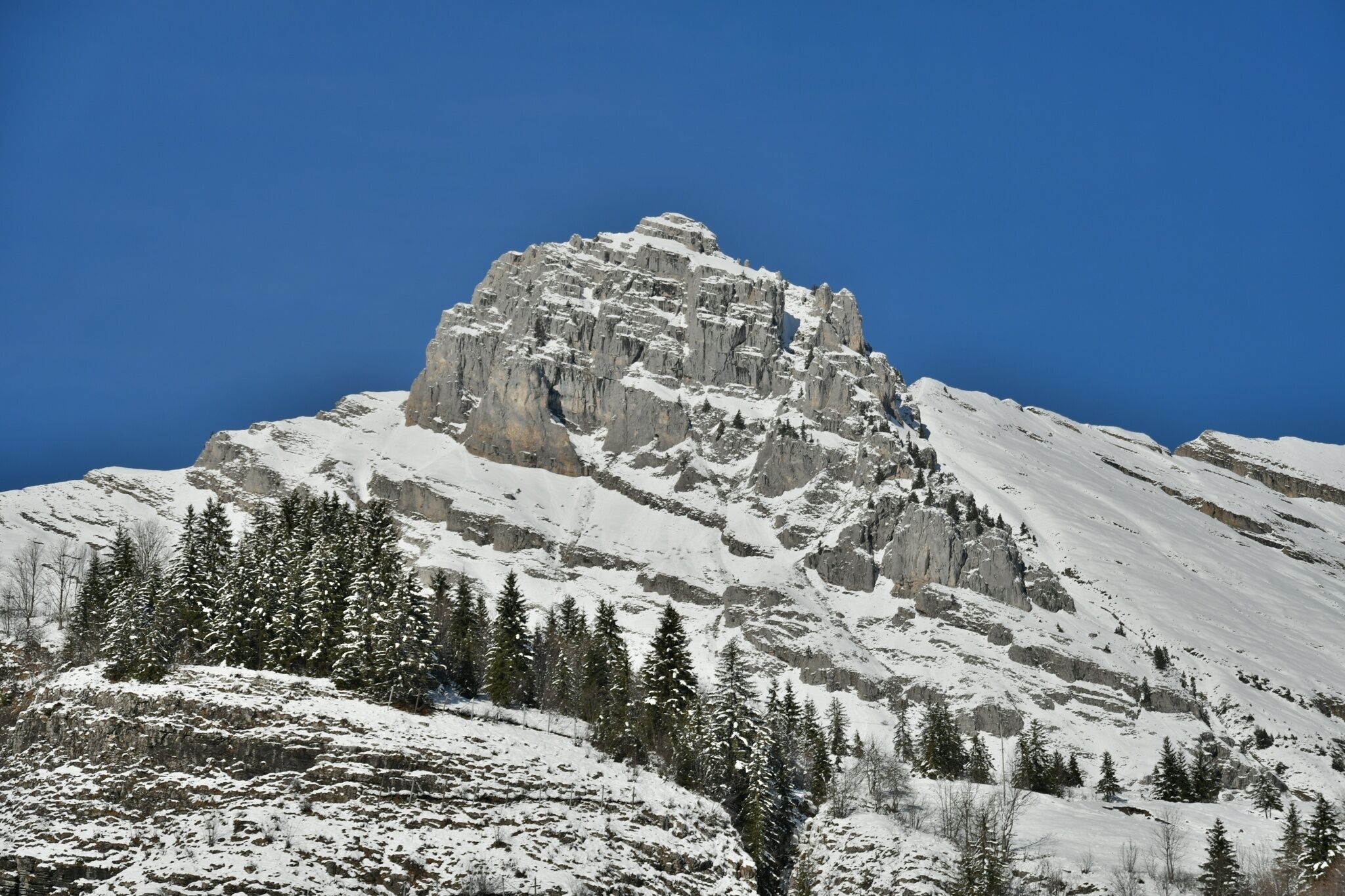 A snow-covered mountain peak with a clear blue sky.
