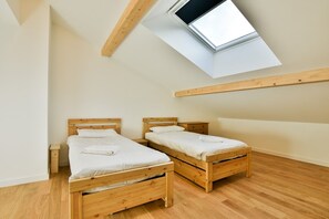 Een slaapkamer met twee houten bedden, een dakraam en een houten vloer.