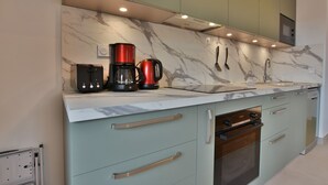 A modern kitchen with marble backsplash, stainless steel appliances, and light green cabinetry. - Le Sève C201 - Three Bedroom Apartment, Sleeps 6 (Samoëns)