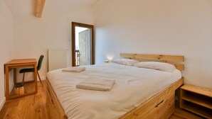 A bedroom with a wooden bed, a small wooden table, and a chair. - Le Sève C201 - Three Bedroom Apartment, Sleeps 6 (Samoëns)