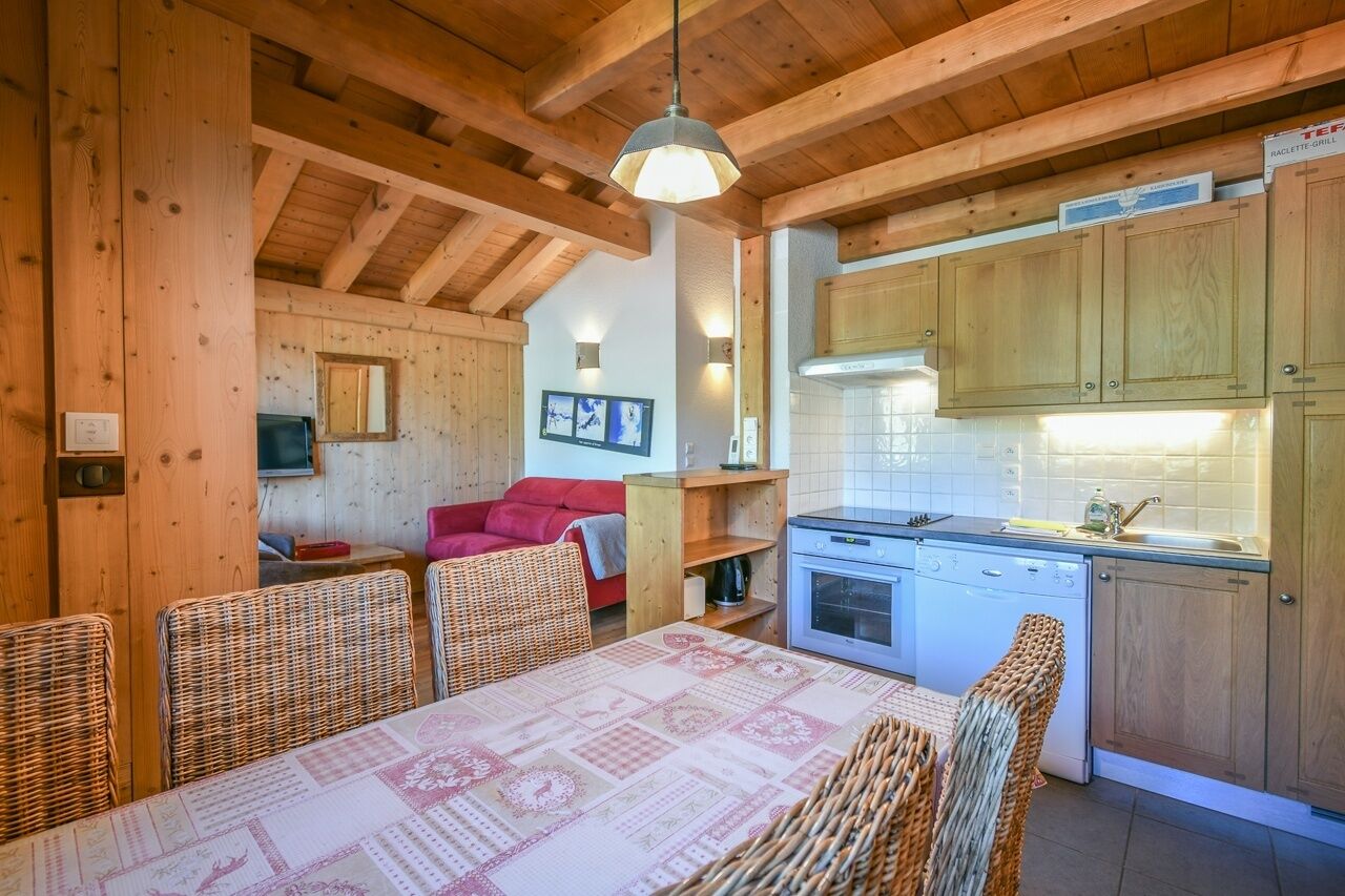 Acogedor interior de cabaña con comedor, cocina y un sofá rojo.