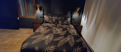 Una camera da letto con un letto, una coperta con motivo a foglia, una testiera scura e lampade ai comodini.