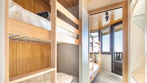 A compact room with bunk beds, a balcony with a view, and a sliding door leading to an outdoor area. - Panoramic 505 - Vue sur la chaîne du Vercors (Chamrousse)