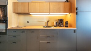 A modern kitchen with wooden cabinets, a stainless steel sink, and a built-in oven. - Panoramic 505 - Vue sur la chaîne du Vercors (Chamrousse)
