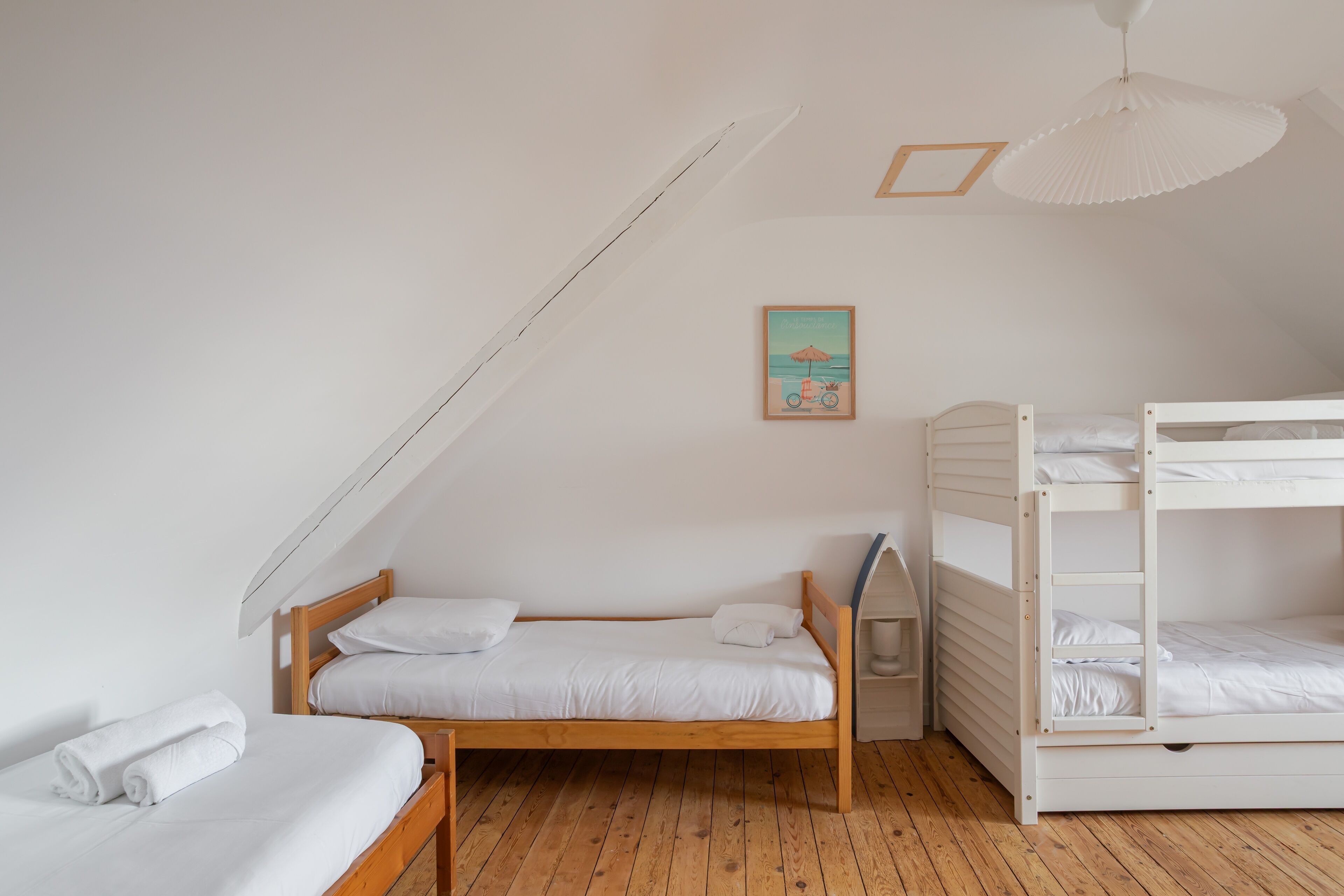 A bedroom with a wooden bunk bed, a single bed, and a ceiling fan.
