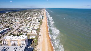Vista aérea de una ciudad costera con una playa extensa, una zona residencial densa y una combinación de edificios comerciales.