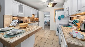 Una cocina moderna con armarios blancos, una isla grande y un ventilador de techo.