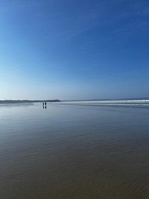 Een breed, vlak strand met een heldere lucht.
