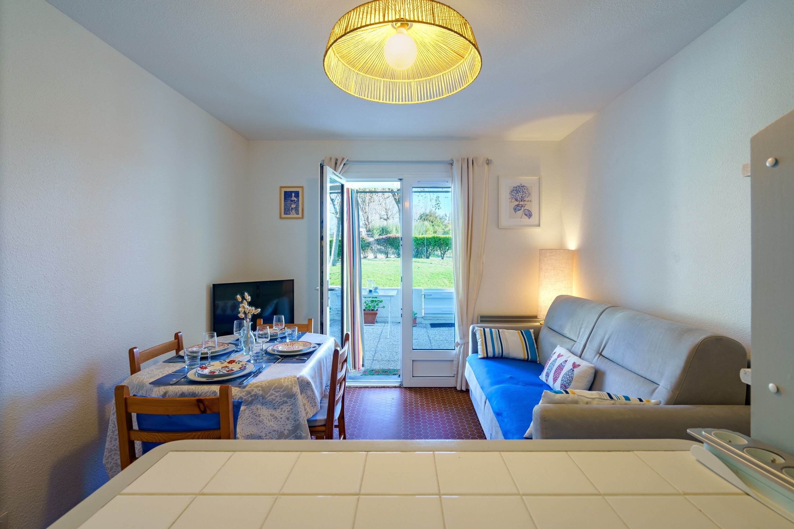 A dining area with a table set for two, a sofa, and a television.