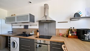 Une cuisine moderne dotée d’une hotte en acier inoxydable, d’un four encastré et d’un lave-linge.