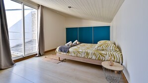 Une chambre moderne avec un lit, une petite table ronde et une vue sur l’extérieur.