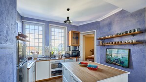 A kitchen with white cabinets, a wooden countertop, and a large window.