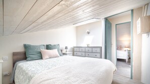 A bedroom with a bed, a dresser, a nightstand, and a door leading to another room. - Le Baiser du Soleil - Piscine Privée (Mirabel-aux-Baronnies)