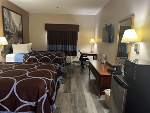 A hotel room with two beds, a desk, a chair, a television, and a bathroom. - Hotel Piney Woods (Huntsville)