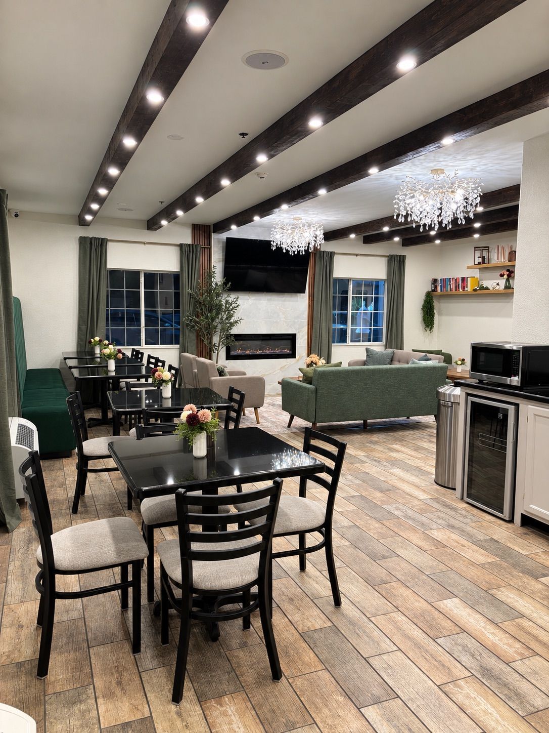 Un salon moderne avec une cheminée, un coin repas avec une table noire et un canapé vert.