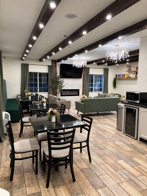 A modern living room with a fireplace, a dining area with a black table, and a green sofa. - Hotel Piney Woods (Huntsville)