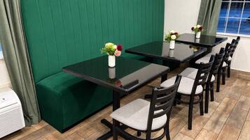 Un área de comedor con un banco tapizado en verde, una mesa con cubierta de vidrio y seis sillas.