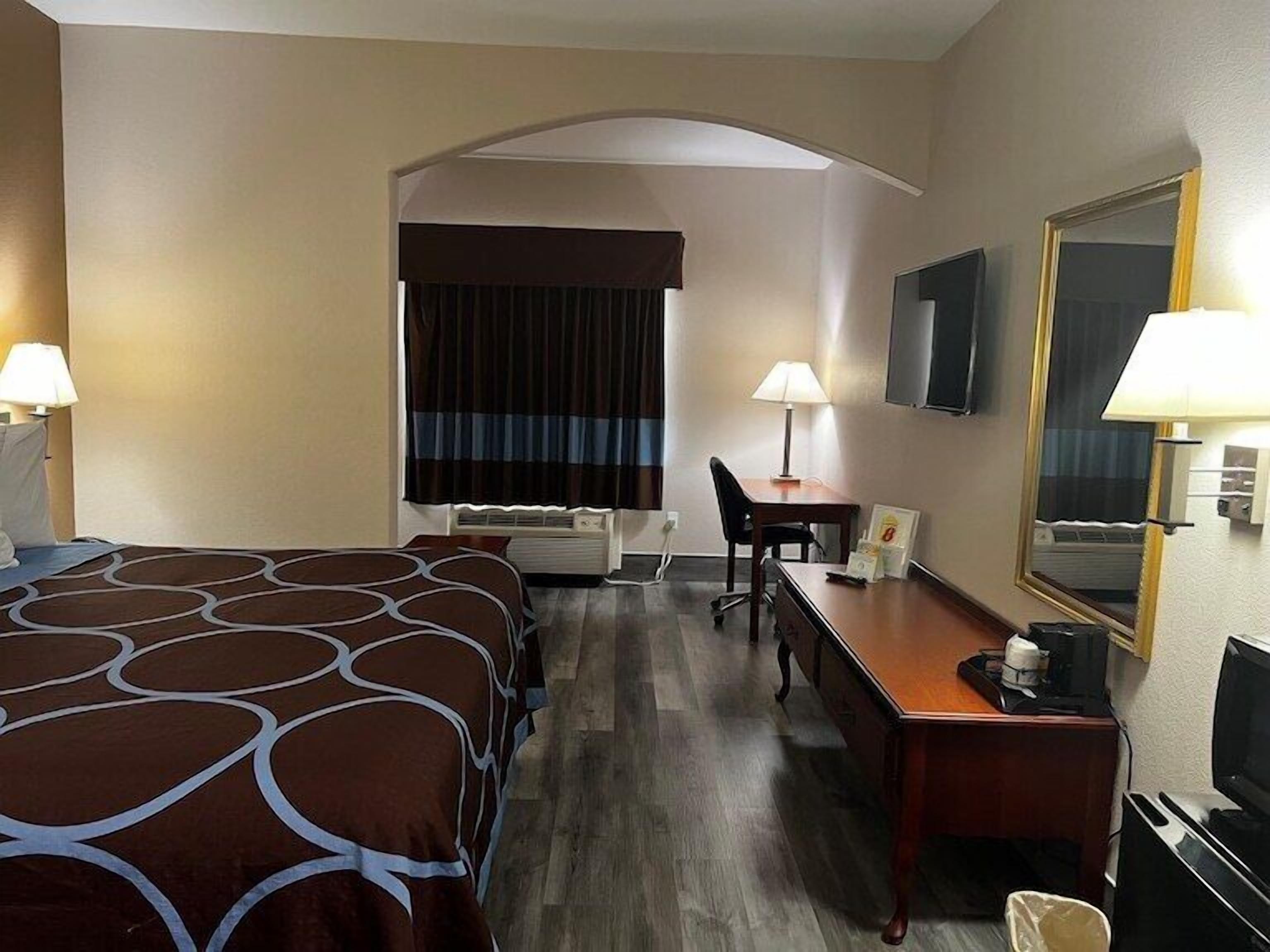 Een hotelkamer met een groot bed, een bureau, een stoel, een televisie en een spiegel.