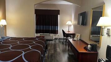 Een hotelkamer met een groot bed, een bureau, een stoel, een televisie en een spiegel.