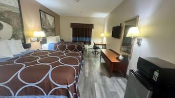 Quarto de hotel com uma cama grande, uma escrivaninha, uma cadeira, uma televisão e um frigorífico.