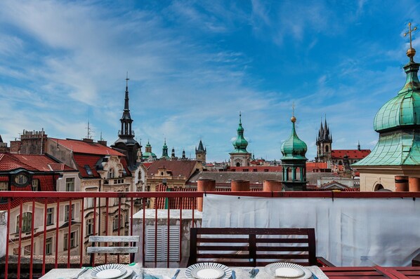A cityscape with historic buildings and domed structures, viewed from a balcony with a table and chairs.