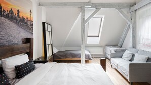 Quarto com cama, sofá, mesa de cabeceira e pintura de paisagem urbana.