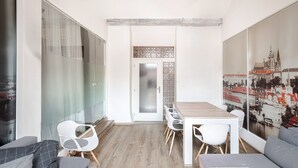 Uma sala de reuniões moderna com divisória de vidro, mesa de madeira, cadeiras brancas e vista para a cidade.