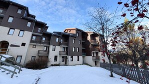 A multi-story residential building with balconies, a snow-covered ground, and a clear sky.