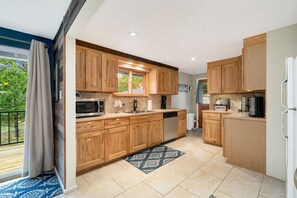 A modern kitchen with wooden cabinets, stainless steel appliances, and a view to the outside.
