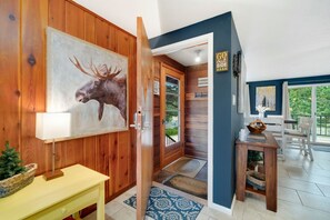 A wooden interior with a moose painting, a door leading outside, and a view of the outdoors. - Perfect Estes Park getaway-The Happy Place Estes,4BD,2Bath,HotTub,PetsOK,EV (Estes Park)