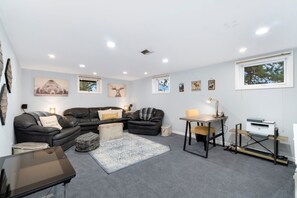 A modern living room with a sofa, armchair, and a small table with a lamp.