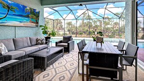Un espace intérieur spacieux avec vue sur la piscine, comprenant un canapé, une table à manger et des chaises.