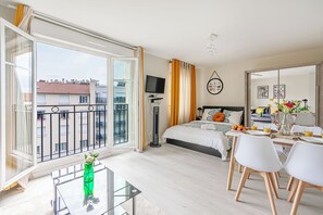 Ett modernt hotellrum med en balkong, en säng, en matplats och en TV.