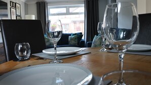 Una mesa de comedor dispuesta con platos, cubiertos y copas de vino, con vistas al exterior a través de una ventana.