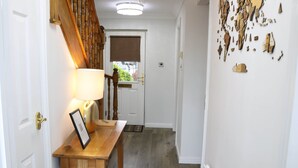 A hallway with a wooden bench, a framed picture, a lamp, and a colorful rug.