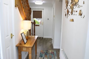 A hallway with a wooden bench, a framed picture, a lamp, and a colorful rug. - Luxury 4 Bedroom Townhouse In Stirling (Stirling)