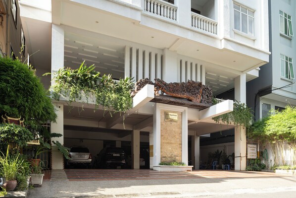 A modern building with a covered entrance, a parking garage, and a sign indicating an apartment complex. - Cozy 2BR Condo with Hardwood Floors & Rooftop Sunset View in Charming Phnom Penh (Phnom Penh)