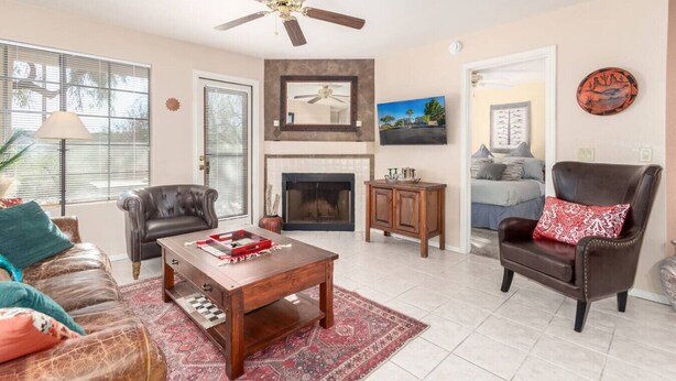 A living room with a fireplace, leather sofas, a coffee table, and a ceiling fan.