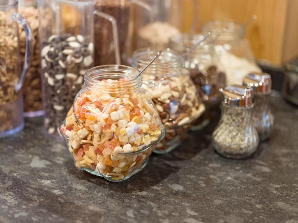 Différents aliments sont présentés dans des récipients en verre sur un plan de travail.