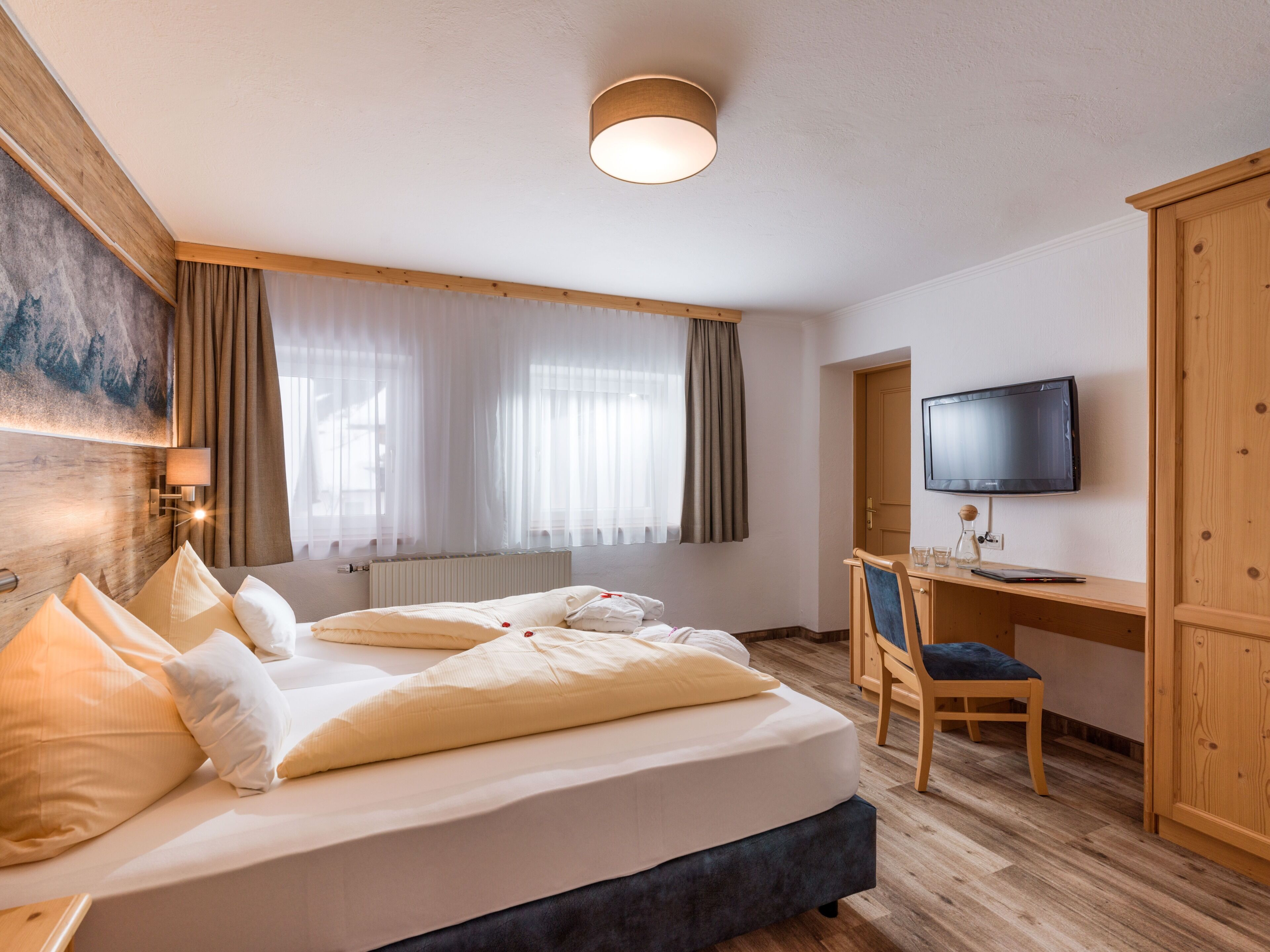 Une chambre d’hôtel équipée d’un lit, d’un bureau, d’une chaise, d’une télévision et d’une fenêtre avec des rideaux.