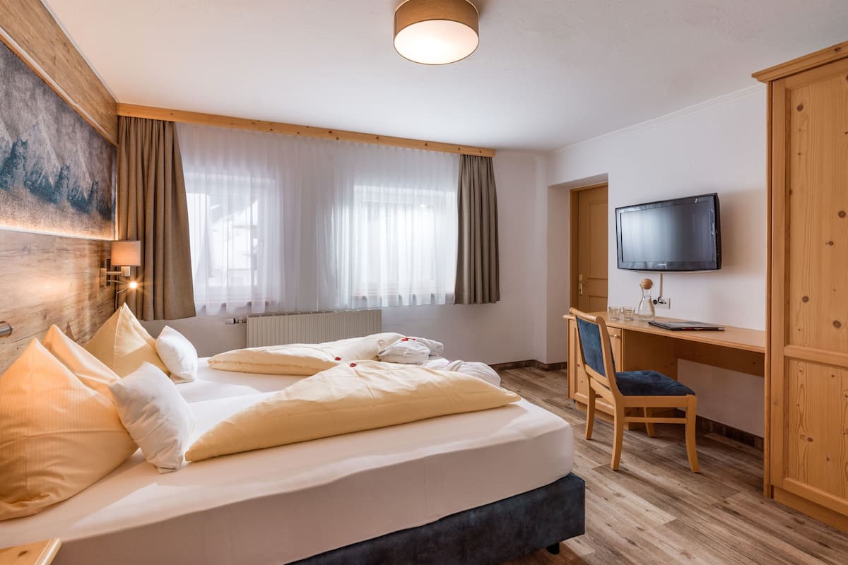 Une chambre d’hôtel équipée d’un lit, d’un bureau, d’une chaise, d’une télévision et d’une fenêtre avec des rideaux.