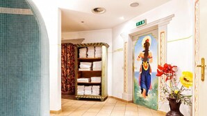 A hotel lobby with a tiled floor, a reception desk, a wall-mounted painting, and a vase with flowers. - Hotel Glockenstuhl (Gerlos)