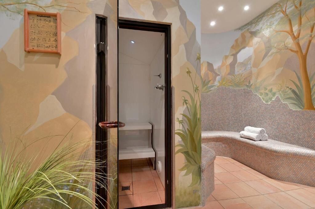 A spa area with a bathtub, a shower, and a wall mural.