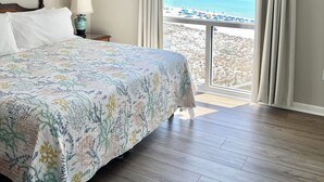 A hotel room with a bed, a lamp, a view of the beach, and a balcony. - Florida Sunshine Beachfront @ Shoreline Towers 3 br condo with beachfront views (Destin)